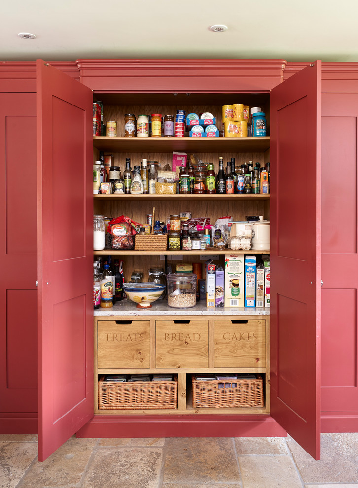 Diseño de cocina campestre con despensa, armarios con paneles empotrados y puertas de armario rojas