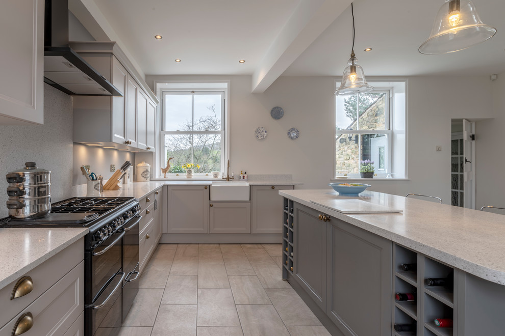 Medium sized traditional kitchen/diner in Cheshire with a belfast sink, shaker cabinets, quartz worktops, black appliances, ceramic flooring, an island, grey floors and grey worktops.
