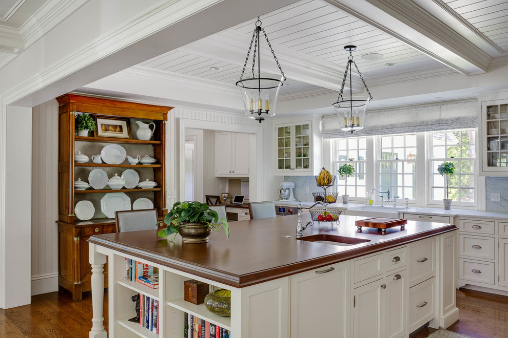 Bild på ett stort vintage vit vitt kök, med en rustik diskho, vita skåp, marmorbänkskiva, vitt stänkskydd, stänkskydd i marmor, mellanmörkt trägolv, en köksö, brunt golv och luckor med profilerade fronter