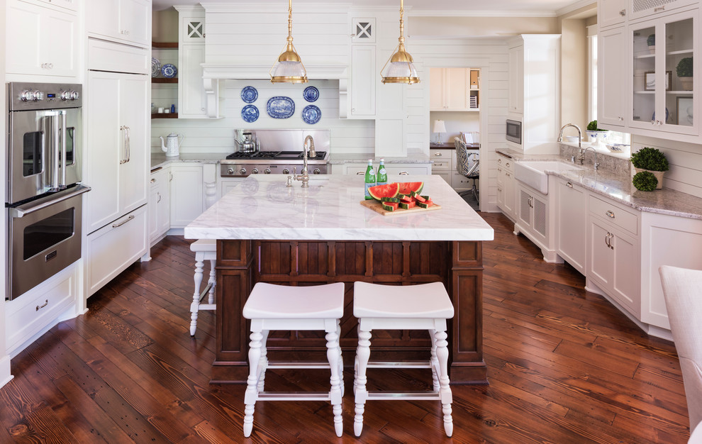 Elegant u-shaped dark wood floor kitchen photo in Minneapolis with a farmhouse sink, shaker cabinets, white cabinets, white backsplash, paneled appliances and an island