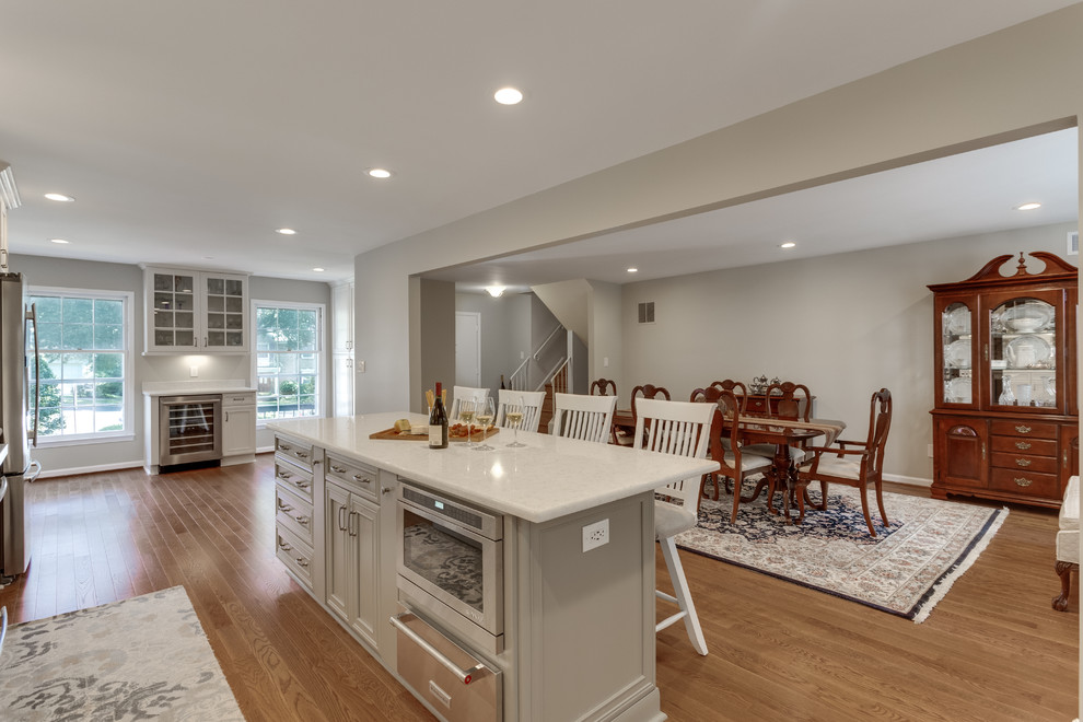 Large traditional galley kitchen in DC Metro with a submerged sink, recessed-panel cabinets, engineered stone countertops, stainless steel appliances, medium hardwood flooring and an island.