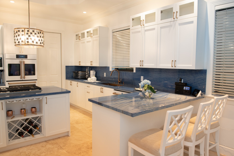На фото: п-образная кухня среднего размера в классическом стиле с обеденным столом, врезной мойкой, фасадами в стиле шейкер, белыми фасадами, синим фартуком, белой техникой, островом и синей столешницей с