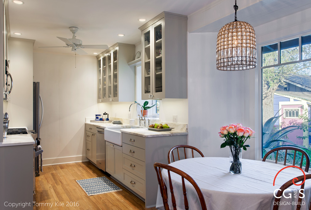 Photo of a small classic galley kitchen/diner in Austin with a belfast sink, shaker cabinets, grey cabinets, marble worktops, marble splashback, stainless steel appliances, medium hardwood flooring and brown floors.