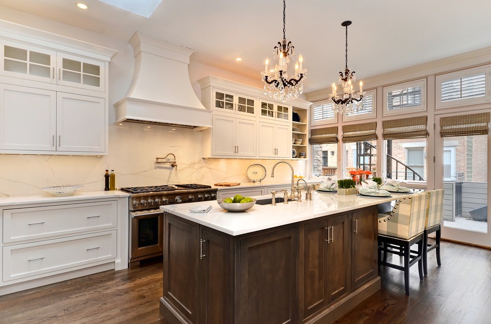 Classic kitchen in Chicago with a submerged sink, white cabinets, white splashback, stainless steel appliances, dark hardwood flooring and an island.