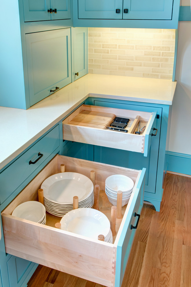 Large traditional galley enclosed kitchen in Portland with a belfast sink, shaker cabinets, blue cabinets, engineered stone countertops, beige splashback, metro tiled splashback, stainless steel appliances, light hardwood flooring and no island.