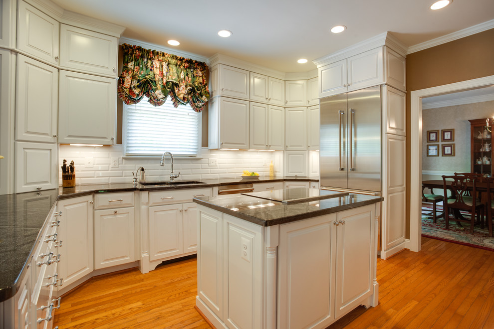 Photo of a large u-shaped enclosed kitchen in DC Metro with a submerged sink, raised-panel cabinets, medium hardwood flooring and an island.