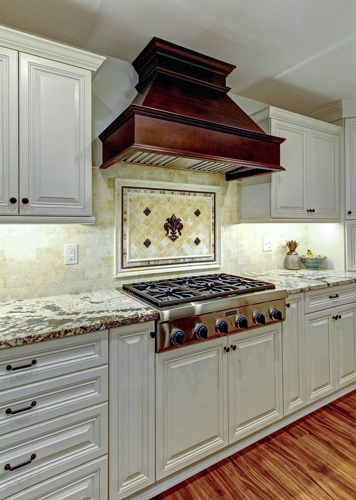 Example of a large classic medium tone wood floor kitchen design in Philadelphia with an undermount sink, raised-panel cabinets, granite countertops, stainless steel appliances and two islands