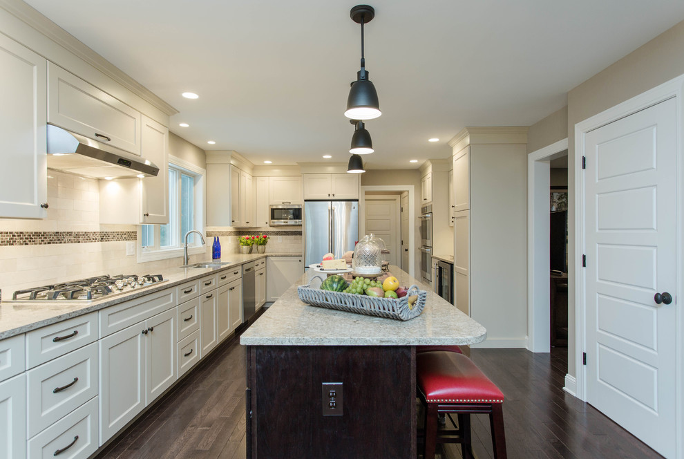 Example of a mid-sized classic l-shaped dark wood floor eat-in kitchen design in Boston with quartz countertops, stainless steel appliances, an island, an undermount sink, shaker cabinets, white cabinets, white backsplash and ceramic backsplash