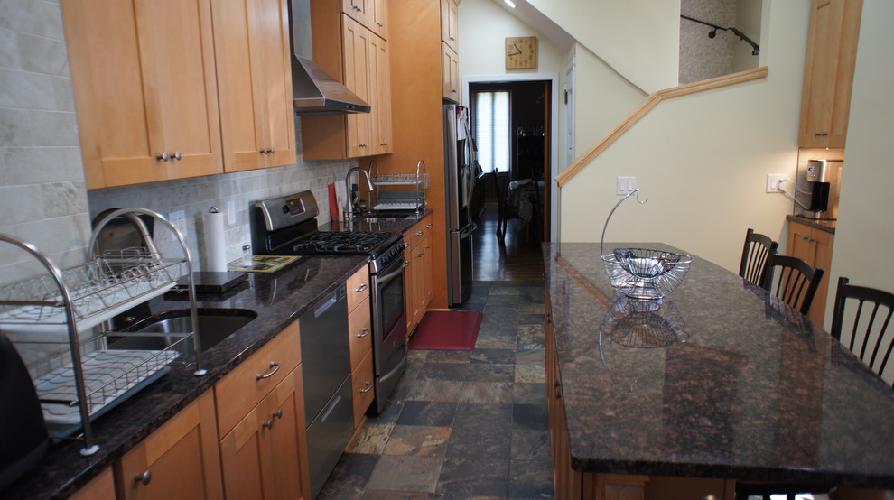 Klassisk inredning av ett avskilt, stort grön linjärt grönt kök, med en undermonterad diskho, luckor med upphöjd panel, skåp i ljust trä, granitbänkskiva, grått stänkskydd, stänkskydd i tunnelbanekakel, rostfria vitvaror, klinkergolv i keramik, en köksö och flerfärgat golv