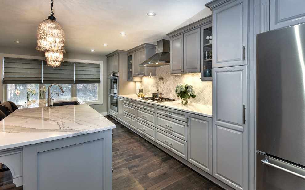 Traditional galley kitchen in DC Metro with a submerged sink, raised-panel cabinets, grey cabinets, engineered stone countertops, stainless steel appliances, dark hardwood flooring, an island and grey splashback.