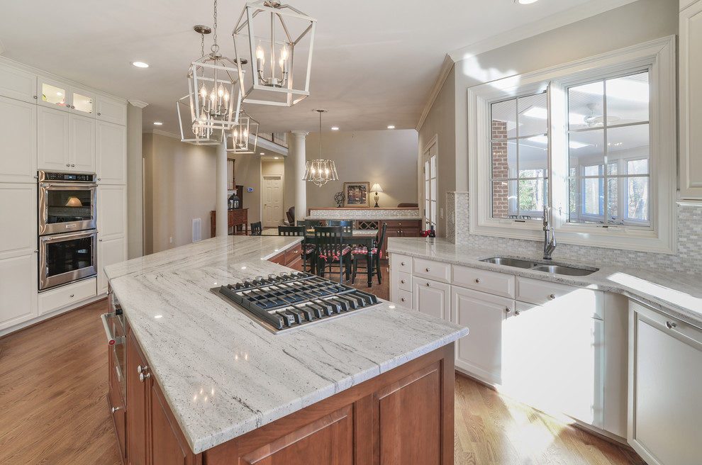 This is an example of a large classic kitchen in DC Metro with a submerged sink, raised-panel cabinets, granite worktops, grey splashback, stainless steel appliances, medium hardwood flooring, an island and grey worktops.