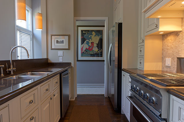 Enclosed kitchen - mid-sized traditional l-shaped medium tone wood floor enclosed kitchen idea in Chicago with an undermount sink, raised-panel cabinets, beige cabinets, quartz countertops, beige backsplash, stone tile backsplash, stainless steel appliances and no island