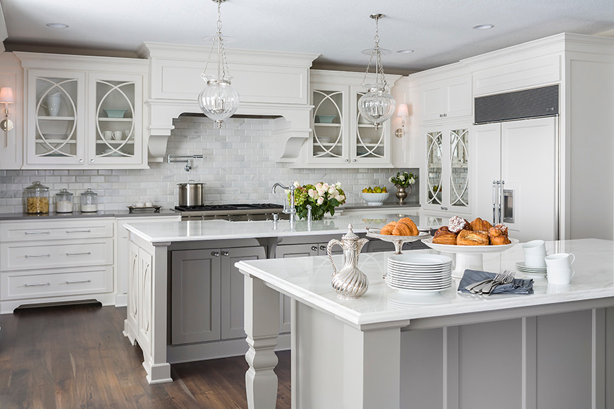 Large classic kitchen in Minneapolis with a belfast sink, flat-panel cabinets, white cabinets, marble worktops, grey splashback, stone tiled splashback, stainless steel appliances and dark hardwood flooring.