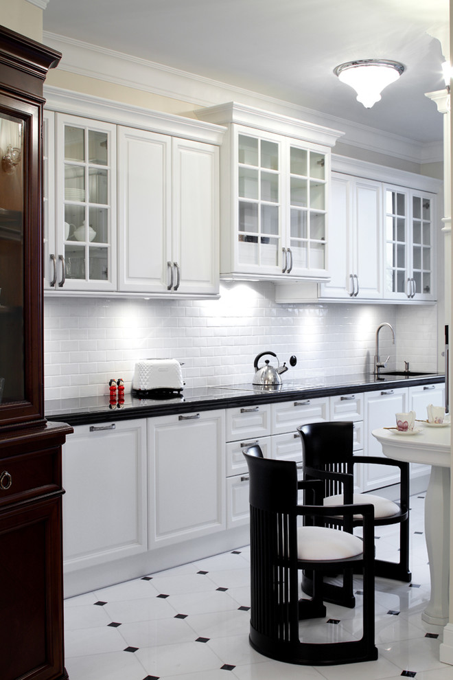 Foto di una cucina classica con lavello sottopiano, ante di vetro, ante bianche, top in granito, paraspruzzi bianco, paraspruzzi in gres porcellanato e elettrodomestici bianchi