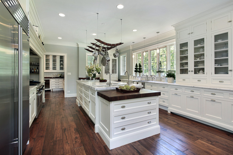 Kitchen pantry - large traditional galley dark wood floor kitchen pantry idea in San Diego with a farmhouse sink, recessed-panel cabinets, white cabinets, marble countertops, white backsplash, stone tile backsplash and an island
