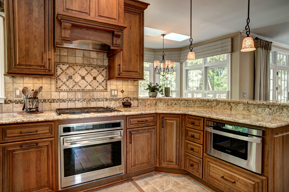 Diseño de cocina clásica con armarios con paneles con relieve, puertas de armario de madera oscura, salpicadero beige y electrodomésticos de acero inoxidable
