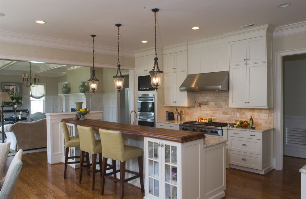 Example of a classic open concept kitchen design in Raleigh with shaker cabinets, wood countertops, white cabinets, beige backsplash and subway tile backsplash