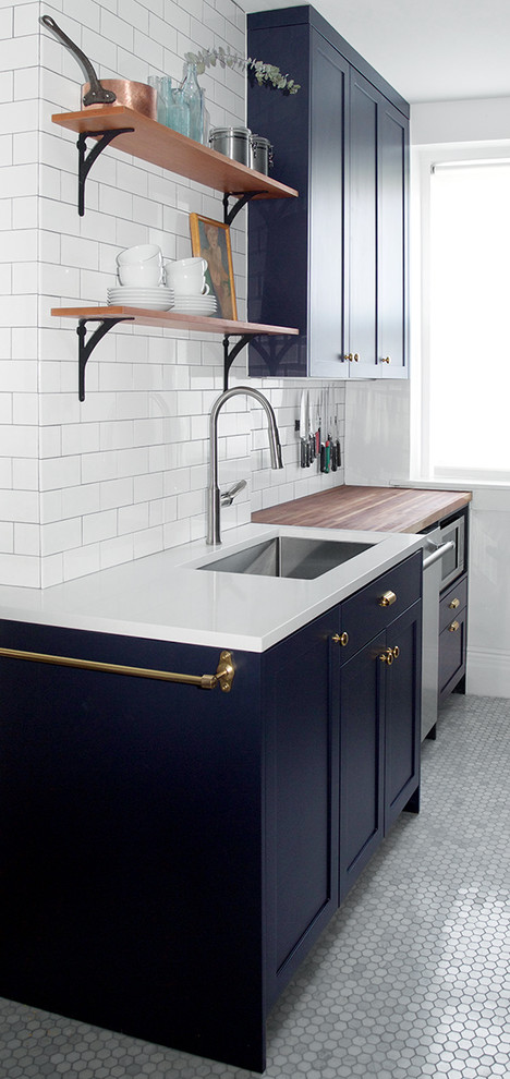Inspiration for a small classic galley enclosed kitchen in New York with a submerged sink, shaker cabinets, blue cabinets, wood worktops, white splashback, metro tiled splashback, stainless steel appliances, marble flooring and no island.