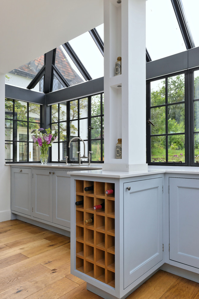 Diseño de cocina clásica renovada con fregadero bajoencimera, armarios estilo shaker, suelo de madera en tonos medios y puertas de armario azules