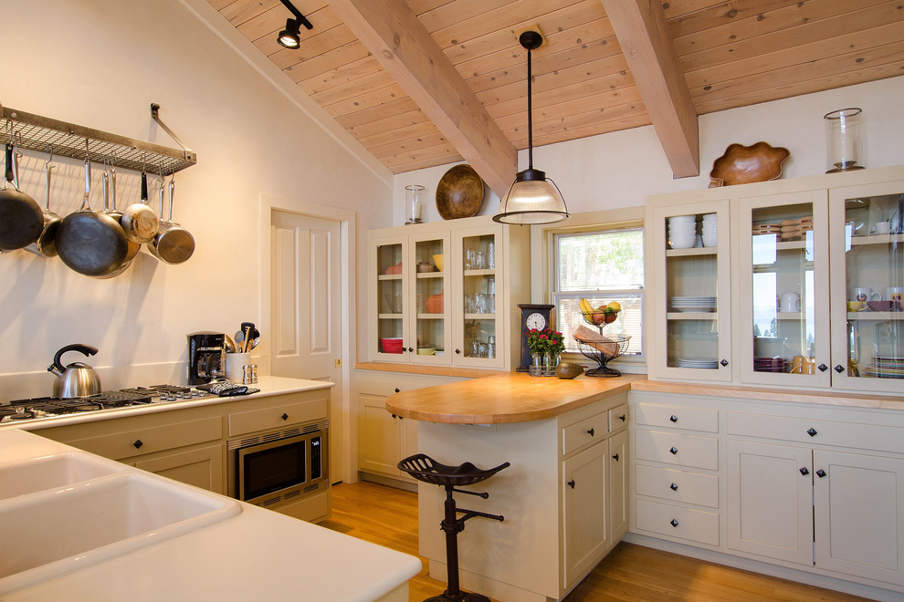 他の地域にあるトラディショナルスタイルのおしゃれなキッチン (ドロップインシンク、ガラス扉のキャビネット、グレーのキャビネット、シルバーの調理設備) の写真