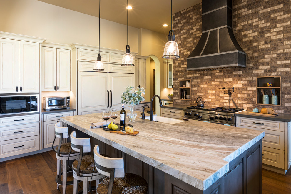 Inspiration for a timeless galley medium tone wood floor and brown floor kitchen remodel with a farmhouse sink, raised-panel cabinets, beige cabinets, gray backsplash, subway tile backsplash, an island and gray countertops