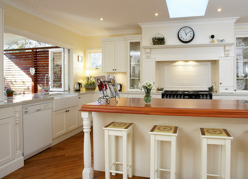 Exempel på ett stort klassiskt kök, med en rustik diskho, träbänkskiva, skåp i shakerstil, vita skåp, vitt stänkskydd, stänkskydd i keramik, vita vitvaror, mellanmörkt trägolv och en köksö