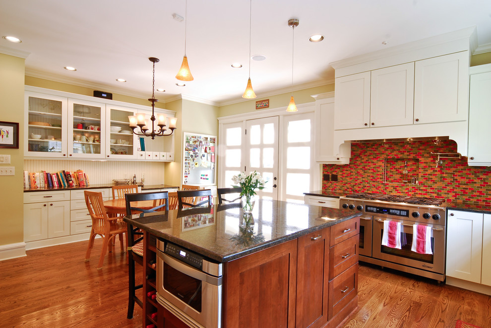 Пример оригинального дизайна: кухня в классическом стиле с обеденным столом, фасадами в стиле шейкер, белыми фасадами, разноцветным фартуком, техникой из нержавеющей стали и фартуком из удлиненной плитки