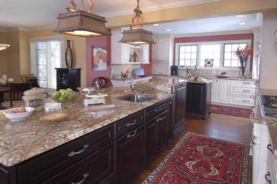 Example of a large classic u-shaped dark wood floor eat-in kitchen design in Other with an undermount sink, raised-panel cabinets, white cabinets, granite countertops, beige backsplash, stone tile backsplash, paneled appliances and two islands