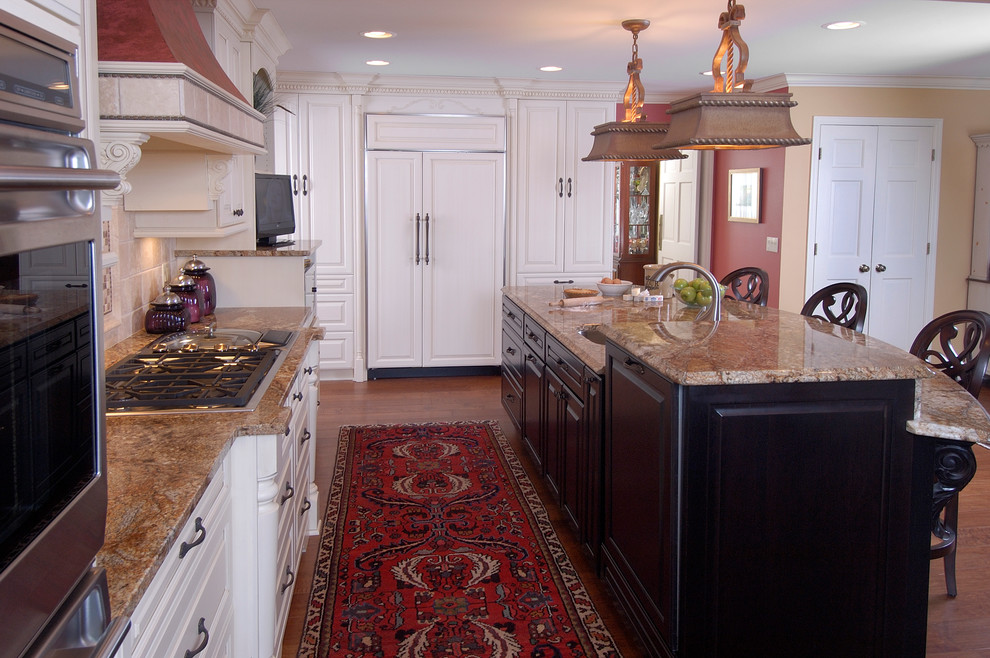 Eat-in kitchen - large traditional u-shaped dark wood floor eat-in kitchen idea in Other with an undermount sink, raised-panel cabinets, white cabinets, granite countertops, beige backsplash, stone tile backsplash, paneled appliances and two islands