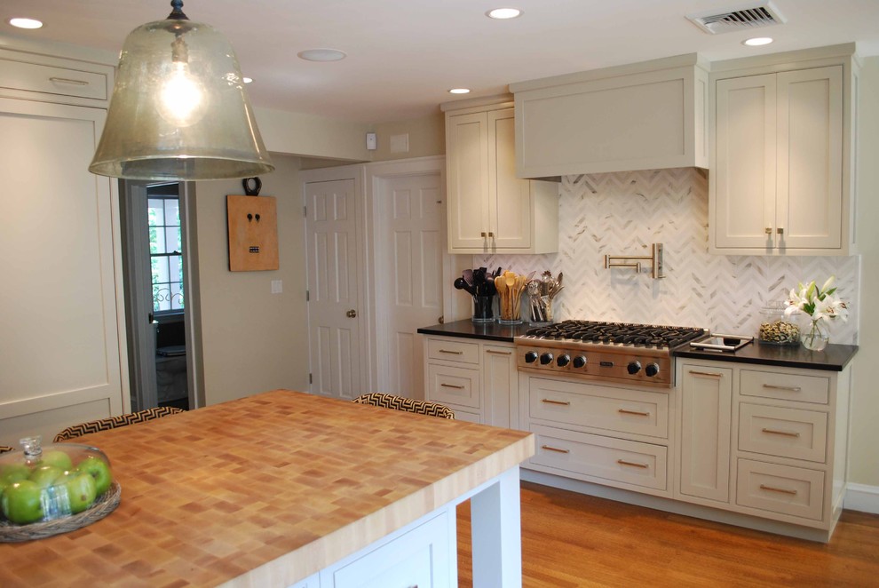 Elegant kitchen photo in Boston with wood countertops, shaker cabinets, beige cabinets, white backsplash, stone tile backsplash and stainless steel appliances