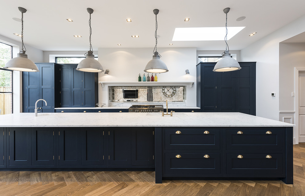Classic galley kitchen in London with shaker cabinets, dark hardwood flooring, an island and blue cabinets.