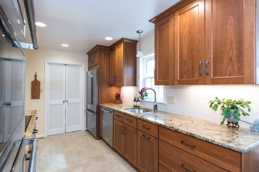 Example of a mid-sized classic galley ceramic tile and beige floor enclosed kitchen design in DC Metro with an undermount sink, shaker cabinets, medium tone wood cabinets, granite countertops, white backsplash, subway tile backsplash, stainless steel appliances and no island