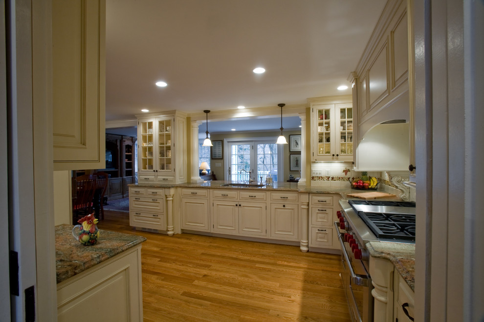 Kitchen pantry - mid-sized traditional l-shaped light wood floor kitchen pantry idea in Boston with an undermount sink, raised-panel cabinets, white cabinets, granite countertops, white backsplash, ceramic backsplash, paneled appliances and no island