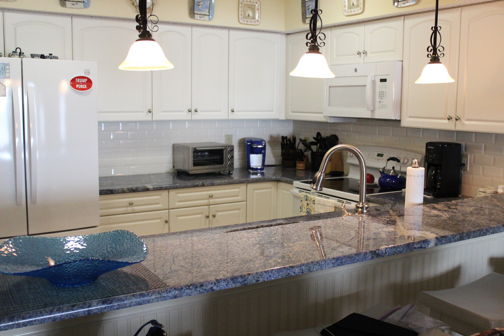 Klassische Küche in U-Form mit Waschbecken, profilierten Schrankfronten, weißen Schränken, Granit-Arbeitsplatte, Küchenrückwand in Weiß, Rückwand aus Metrofliesen, Halbinsel und blauer Arbeitsplatte in New York