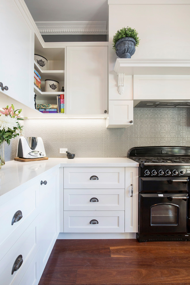 Exempel på ett mellanstort klassiskt vit vitt kök, med en rustik diskho, skåp i shakerstil, vita skåp, bänkskiva i kvarts, grått stänkskydd, stänkskydd i keramik, svarta vitvaror, mellanmörkt trägolv, en köksö och brunt golv