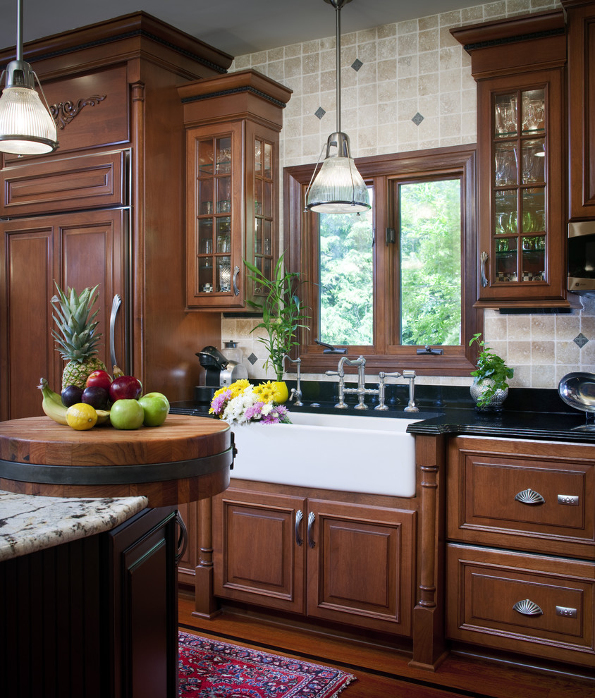 Mid-sized elegant l-shaped medium tone wood floor eat-in kitchen photo in Chicago with a farmhouse sink, raised-panel cabinets, medium tone wood cabinets, granite countertops, white backsplash, porcelain backsplash, stainless steel appliances and an island