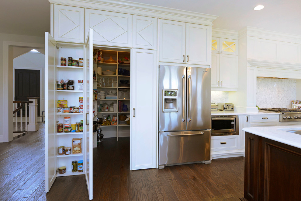 Kitchen pantry - traditional dark wood floor and brown floor kitchen pantry idea in Other with an integrated sink, recessed-panel cabinets, white cabinets, quartzite countertops, gray backsplash, glass tile backsplash, stainless steel appliances, an island and white countertops