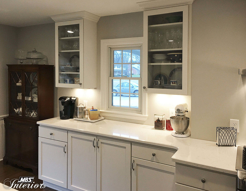 This is an example of a large classic grey and cream l-shaped kitchen/diner in Detroit with a submerged sink, white cabinets, granite worktops, stainless steel appliances, light hardwood flooring, an island, shaker cabinets, grey splashback and beige floors.