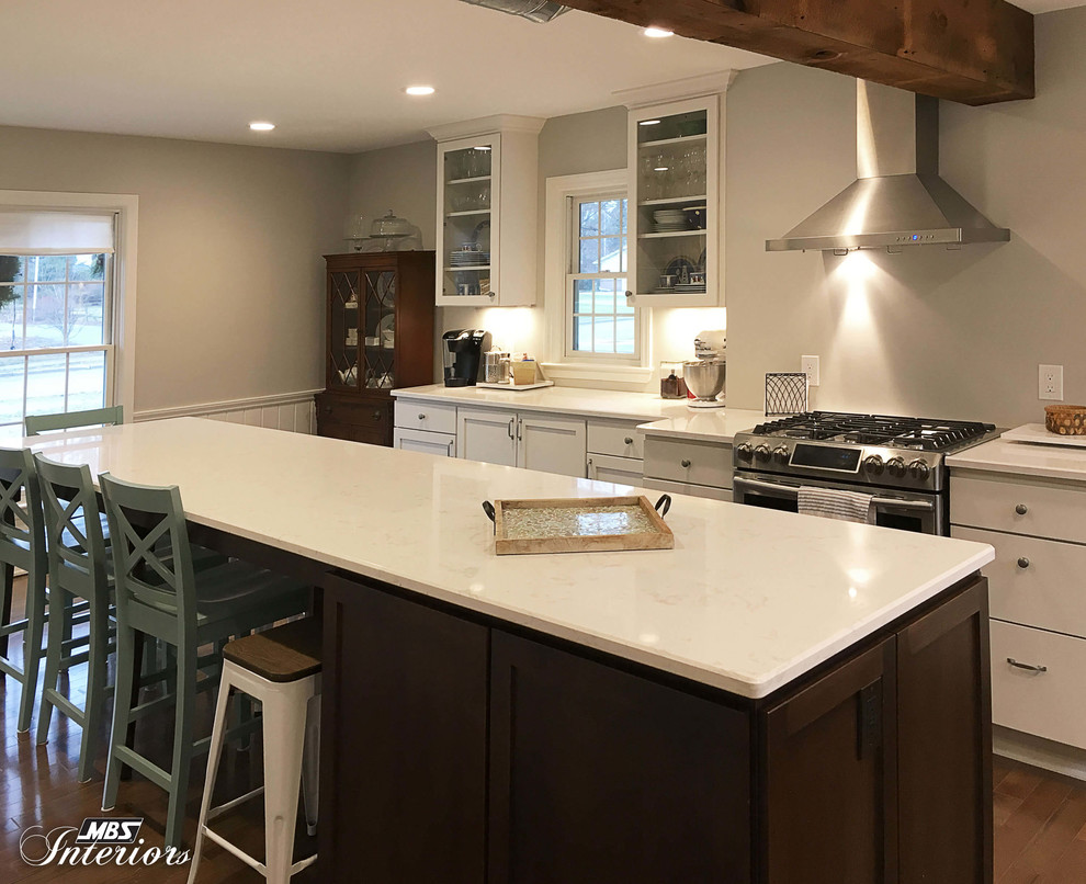 This is an example of a large classic grey and cream l-shaped kitchen/diner in Detroit with a submerged sink, white cabinets, granite worktops, stainless steel appliances, light hardwood flooring, an island, shaker cabinets, grey splashback and beige floors.