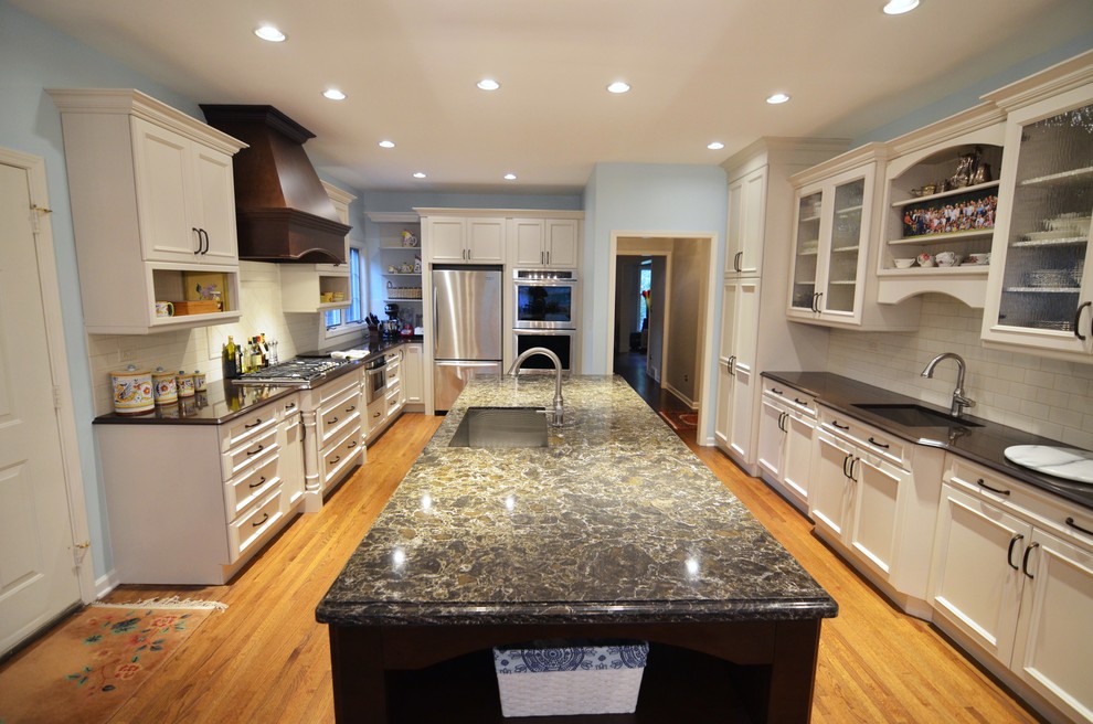 Inspiration for a large timeless l-shaped medium tone wood floor enclosed kitchen remodel in Chicago with an undermount sink, raised-panel cabinets, white cabinets, quartz countertops, white backsplash, subway tile backsplash, stainless steel appliances and an island