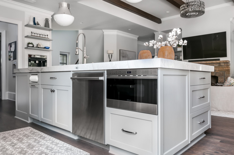 Inspiration for a large classic l-shaped kitchen/diner in Atlanta with a single-bowl sink, shaker cabinets, white cabinets, quartz worktops, white splashback, stainless steel appliances, medium hardwood flooring, an island, brown floors and white worktops.