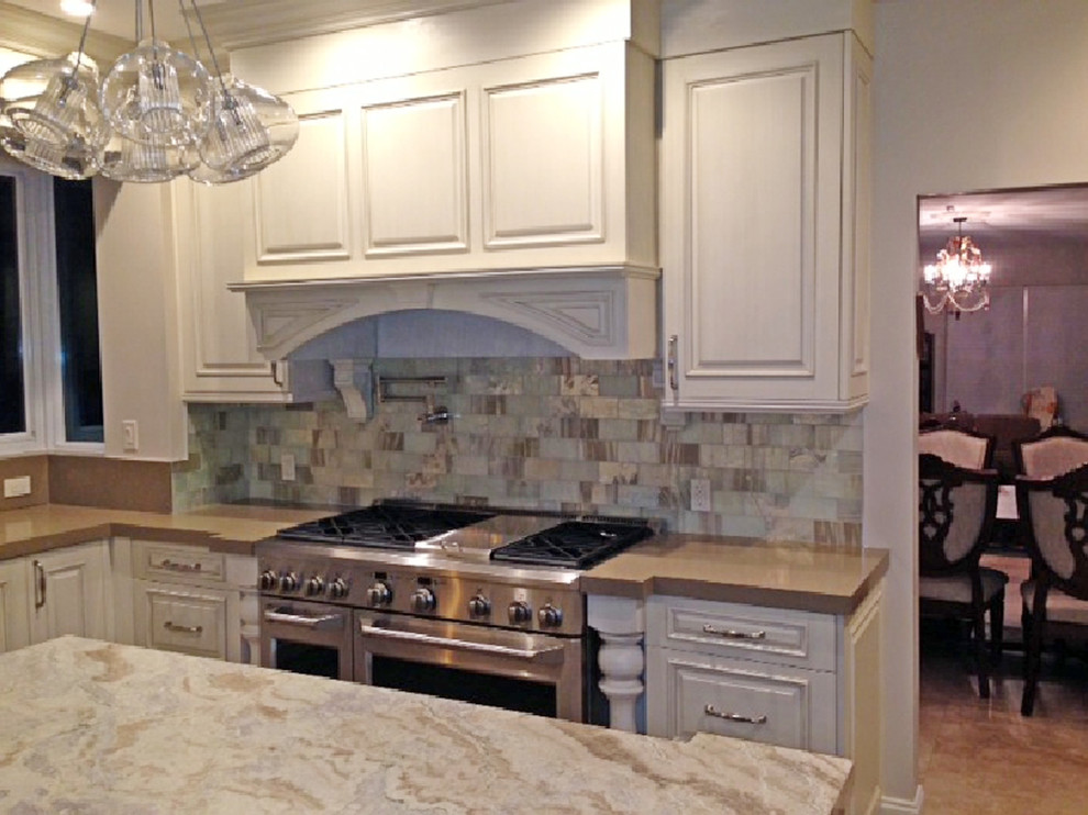 Exempel på ett avskilt, stort klassiskt l-kök, med luckor med infälld panel, vita skåp, marmorbänkskiva, flerfärgad stänkskydd, stänkskydd i glaskakel, rostfria vitvaror, travertin golv och en köksö