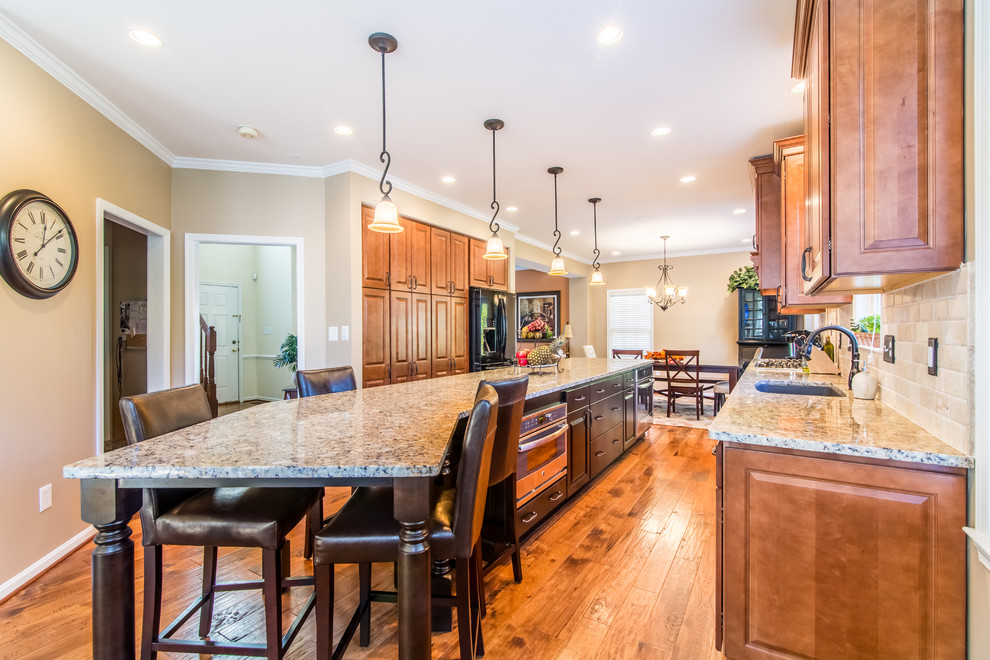 Large elegant galley medium tone wood floor and brown floor eat-in kitchen photo in DC Metro with a single-bowl sink, raised-panel cabinets, medium tone wood cabinets, quartz countertops, beige backsplash, stone tile backsplash, black appliances and an island