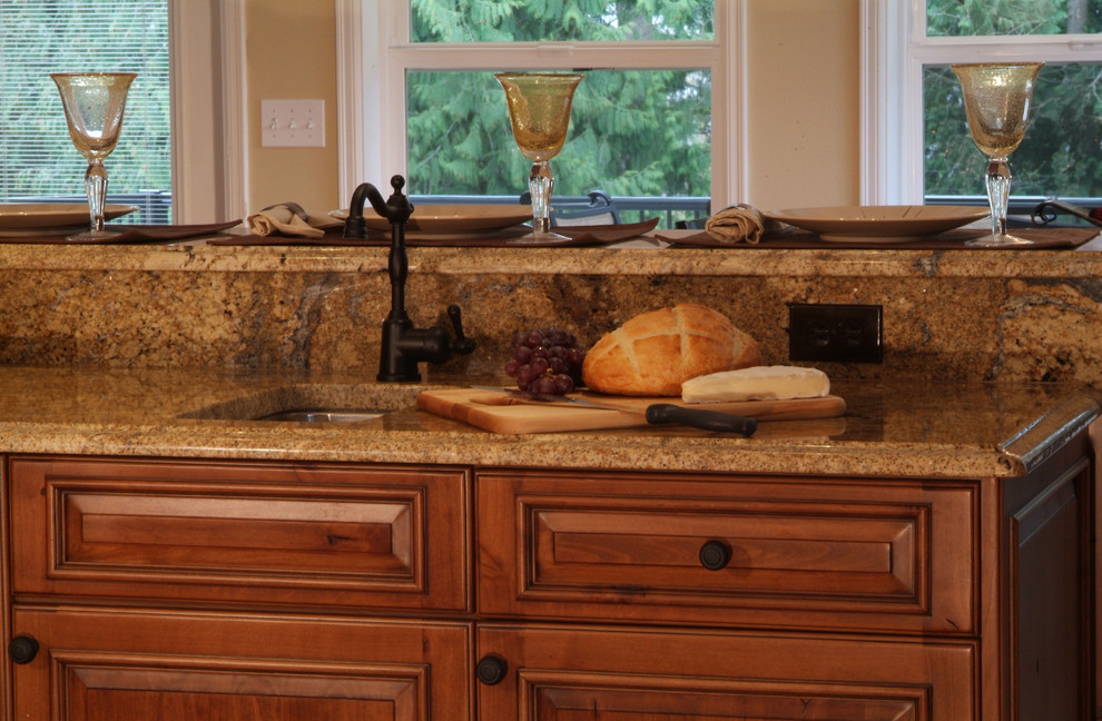 Exempel på ett mellanstort klassiskt kök, med en undermonterad diskho, luckor med upphöjd panel, skåp i mellenmörkt trä, granitbänkskiva, beige stänkskydd, stänkskydd i sten, rostfria vitvaror, mellanmörkt trägolv och en köksö