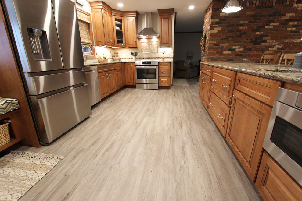 Example of a mid-sized transitional galley vinyl floor and gray floor eat-in kitchen design in Cleveland with an undermount sink, raised-panel cabinets, medium tone wood cabinets, quartz countertops, beige backsplash, limestone backsplash, stainless steel appliances, a peninsula and beige countertops