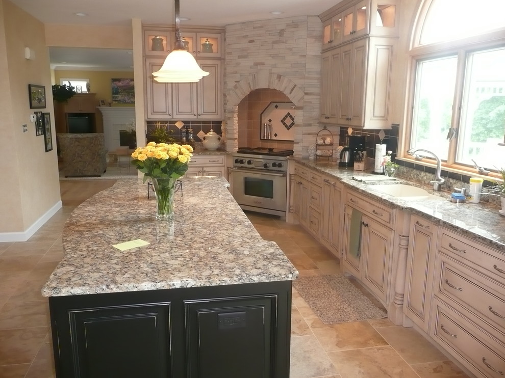 Klassisk inredning av ett kök och matrum, med en undermonterad diskho, beige skåp, granitbänkskiva och integrerade vitvaror