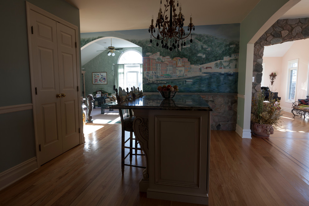 Mid-sized tuscan l-shaped light wood floor eat-in kitchen photo in Bridgeport with a farmhouse sink, raised-panel cabinets, beige cabinets, granite countertops, beige backsplash, stone tile backsplash, stainless steel appliances and two islands