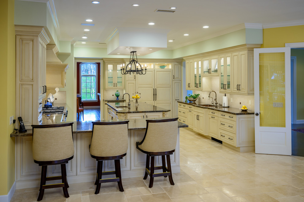 Example of a huge classic l-shaped travertine floor eat-in kitchen design in Los Angeles with an undermount sink, raised-panel cabinets, beige cabinets, granite countertops, beige backsplash, travertine backsplash, stainless steel appliances and an island