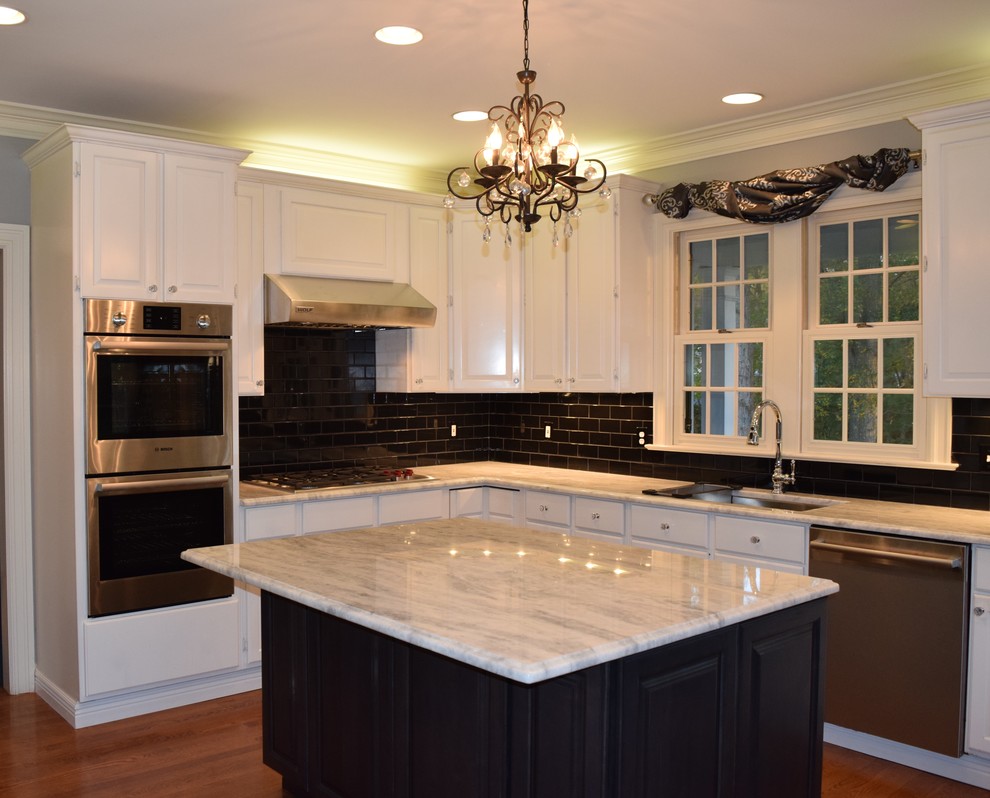 Example of a large classic u-shaped medium tone wood floor eat-in kitchen design in Baltimore with an undermount sink, raised-panel cabinets, white cabinets, granite countertops, black backsplash, subway tile backsplash, stainless steel appliances and an island