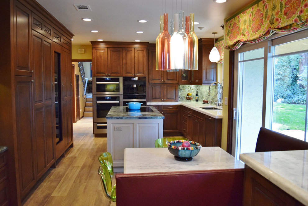 Idéer för att renovera ett mellanstort vintage vit vitt kök, med en undermonterad diskho, luckor med upphöjd panel, skåp i mörkt trä, bänkskiva i kvarts, flerfärgad stänkskydd, stänkskydd i glaskakel, rostfria vitvaror, mellanmörkt trägolv, en köksö och brunt golv